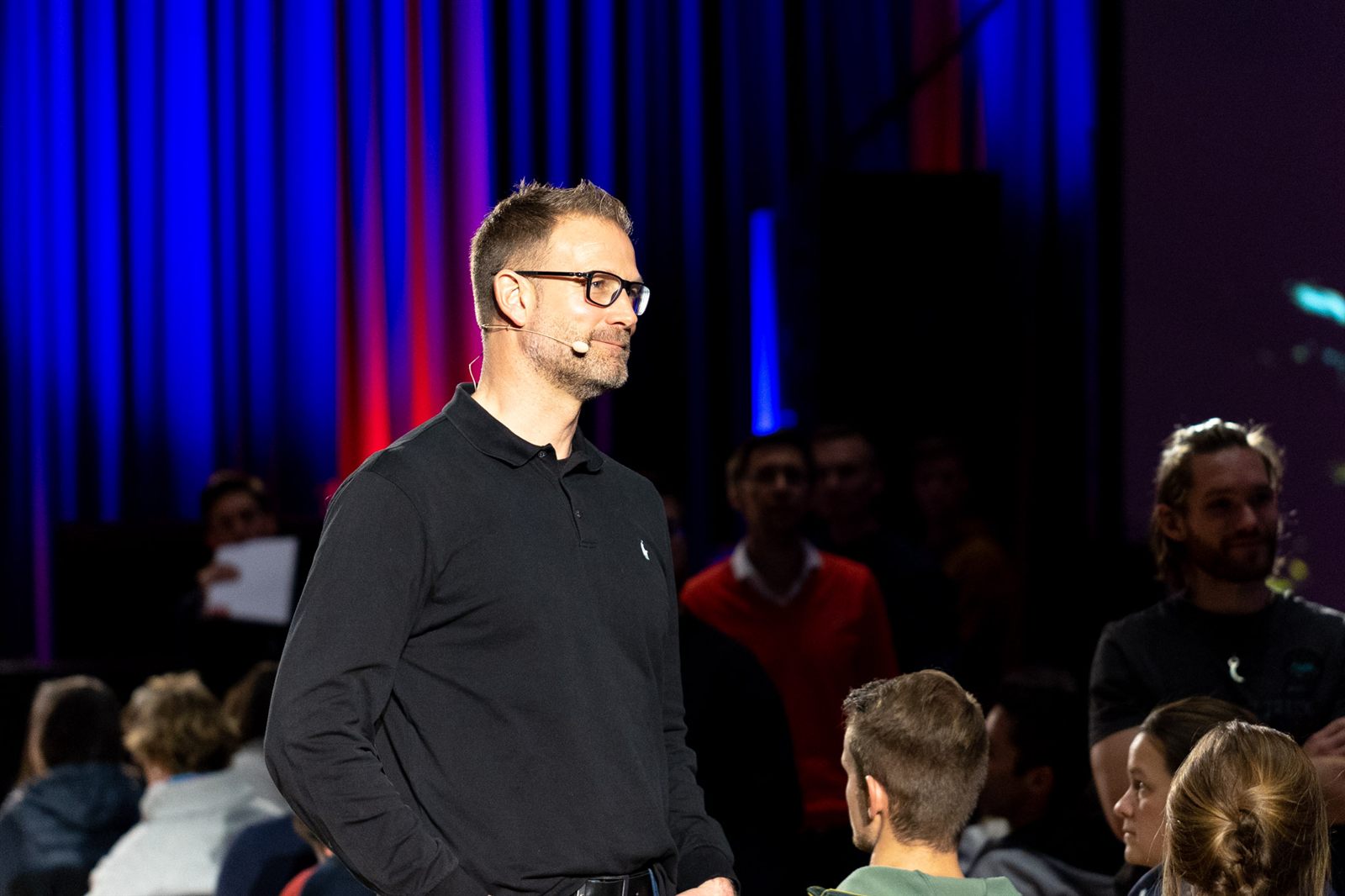 Christian Bischoff steht lächelnd mitten im Publikum